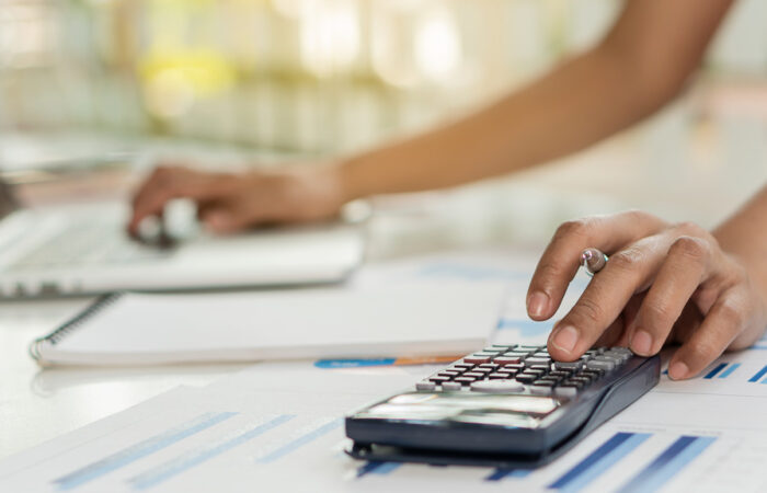 EMpreendedora fazendo cálculo em calculadora e usando notebook para emitir nota fiscal em SP