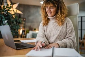 Mulher sorridente em escritório, realizando emissão da DANFE.