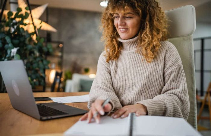 Mulher sorridente em escritório, realizando emissão da DANFE.