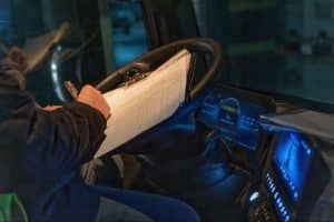 Motorista escrevendo com caneta em folha de papel, representando CTe OS.