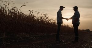 Silhueta de dois homens apertando as mãos após análise de crédito rural.