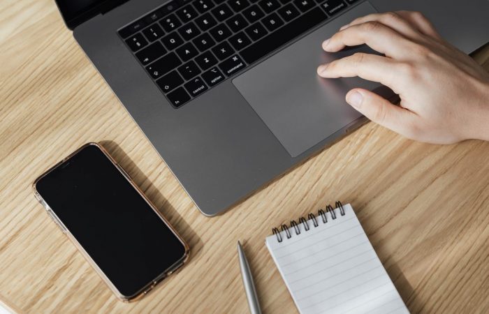 Pessoa usando notebook com celular e bloquinho de notas com caneta ao lado, simbolizando Difal ICMS