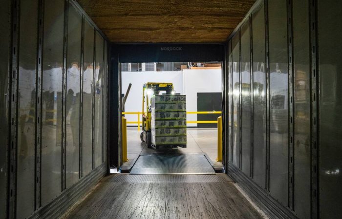 Empilhadeira com mercadorias entrando em container ou depósito, simbolizando damdfe