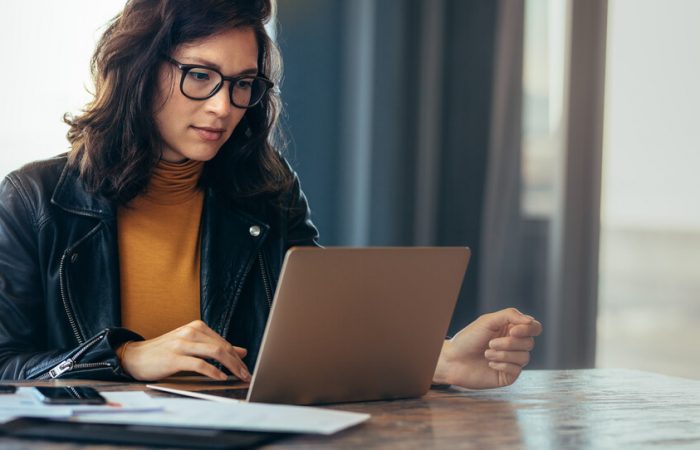 Mulher de óculos de grau usando notebook, simbolizando Nota fiscal denegada