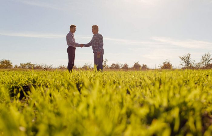 donos de empresa rural dando as mãos em meio à fazenda