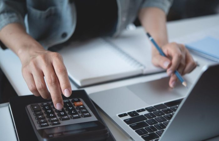 pessoa usando notebook e calculadora para saber como calcular imposto de nota fiscal
