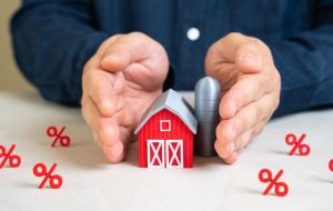 pessoa segurando casa em miniatura, representando a tributação no agronegócio