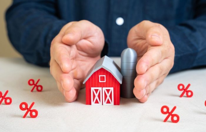 pessoa segurando casa em miniatura, representando a tributação no agronegócio